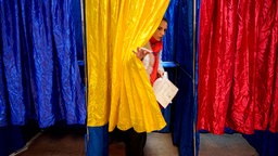 Frau verlässt eine Wahlkabine in Bukarest, Rumänien, 01.12.2024. 