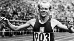 Schwarz-weiß-Foto von 1952: Der Läufer Emil Zatopek läuft freudestrahlend ins Ziel ein. 