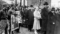 Alfred Hugenberg (Bildmitte mit Melone), DNVP-Vorsitzender und Reichsminister, wartet mit anderen Wählern in einer Schlange vor einem Wahllokal