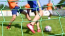 Kinder spielen auf einem Sportplatz Fußball