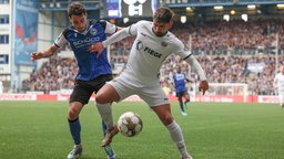 Christopher Lannert (l) im Kampf um den Ball mit Münsters Malik Batmaz (r).