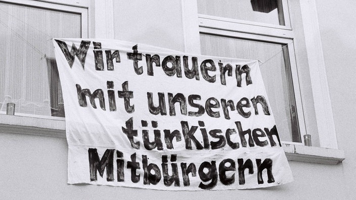 Ein Laken mit der Aufschrift "WIr trauern mit unseren türkischen Mitbürgern" hängt aus einem Fenster