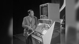 Der britische Sänger, Schauspieler, Radiomoderator und Fernsehmoderator Chris Howland an einer Wurlitzer Musikbox.