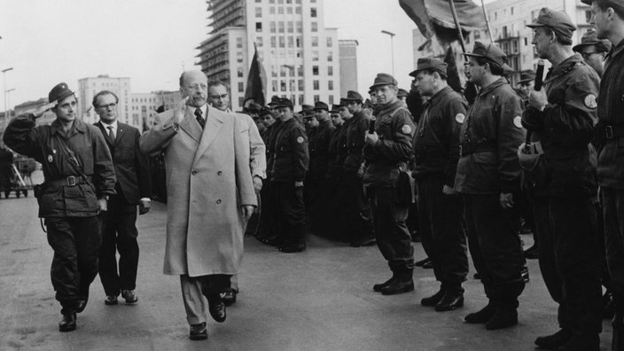 Appell der Berliner Kampfgruppen an der Ost-Berliner Stalinallee am 23.08.1961; Walter Ulbricht (erster Sekretär des ZK der SED) schreitet die Front ab, dahinter Erich Honecker (für den Mauerbau verantwortlicher ZK-Sekretär für Sicherheit)