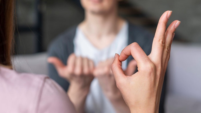 Zwei Menschen unterhalten sich in Gebärdensprache