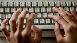 Finger tippen auf einer Computer-Tastatur.