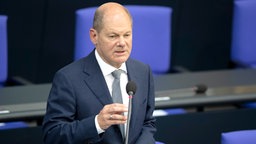 Bundesfinanzminister Olaf Scholz steht hinter einem Mikro