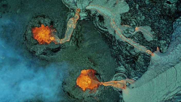 Das Foto zeigt aus der Vogelperspektive zwei Vulkankrater, aus denen Lava fließt.