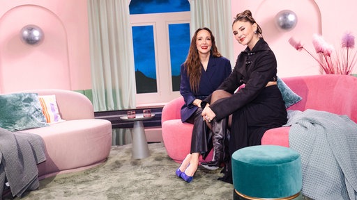 Carolin Kebekus sitzt gemeinsam mit Stefanie Giesinger auf der Couch. Beide lächeln in die Kamera.