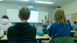 Zwei Schüler sitzen in der Schule und hören dem Lehrer zu