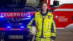 Feuerwehrmann Simon Heußen vor Feuerwehreinsatzwagen