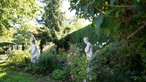 Axl Jansen Gartten mit Rosen und Deko-Statuen.