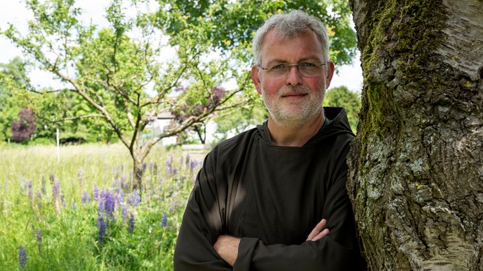 Kapuziner Bruder Bernd lehnt an einem Baum.