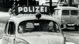 sw-Foto, zwei Polizisten fahren in einem Polizei-VW-Käfer