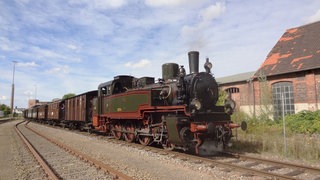 Ein historischer Dampfzug steht am Bahnhof