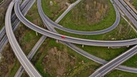 Luftaufnahme von einem Autobahnkreuz, auf dem nur ein rotes Auto zu sehen ist