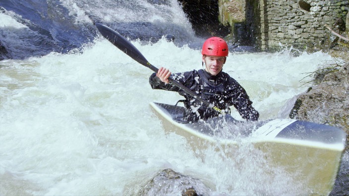 Ein Kanufahrer im tosenden Wasser einer Wildwasserstrecke.