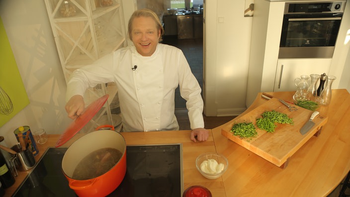 Sternekoch Björn Freitag vor einem dampfenden Kochtopf