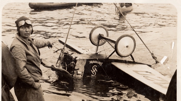 Thea Rasche vor ihrem im Wasser liegenden Flugzeug