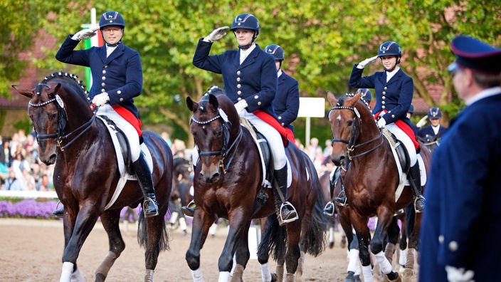 Mehrere Reiterinnen in Uniformen paradieren an der Kamera vorbei