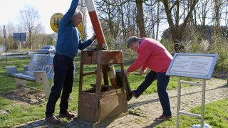 Zwei Männer schließen einen Grenzbaum