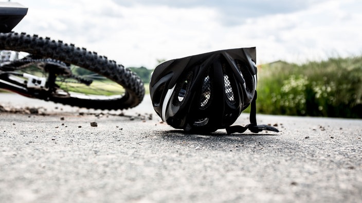 Fahrradhelm und Fahrrad liegen auf der Straße, Symbolbild