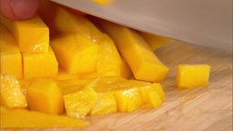 Lars Middendorf schneidet Mango in den frischen Kartoffelsalat.