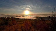 Blick auf die Medebacher Bucht, die im Nebel von der aufgehenden Sonne beschienen wird.