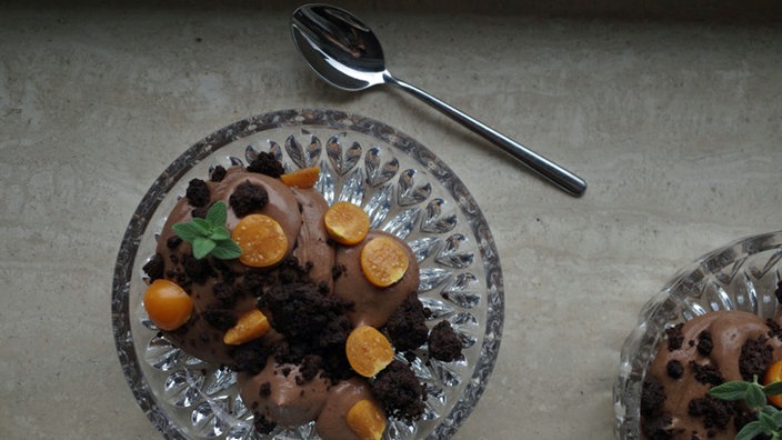 Nougatmousse in einem Glas mit Schoko-Crumble, daneben ein Löffel