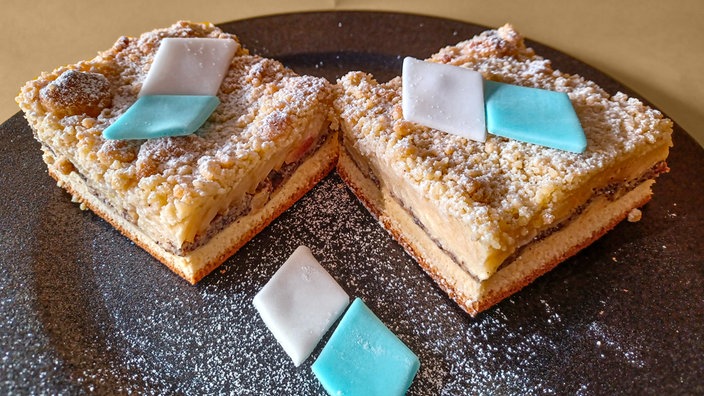 Zwei Stücke Apfel-Mohnstreusel mit weißen und blauen Romben aus Zucker verziert