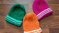 Je eine grüne, rosa- und orangefarbene Strickmütze