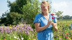 Anna Pröbstle inmitten von Blumen auf dem Feld. 