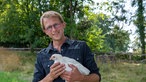  Lukas Tölkes mit einem Huhn auf dem Arm. 