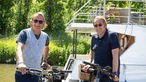 Frank Buchholz und Björn Freitag stehen mit den Rädern vor dem Boot. 