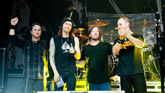 Bandmitglieder von Alter Bridge stehen auf der Bühne und verabschieden sich vom Publikum