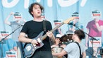 Gitarrist von The Wombats spielt lässig auf seiner Gitarre und schaut verlassen Richtung Publikum