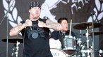 Sänger von Agnostic Front mit großem Stirmband macht eine feurige Geste mit zugekniffenen Augen