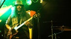 Brant Bjork steht im Scheinwerferlicht und spielt Gitarre