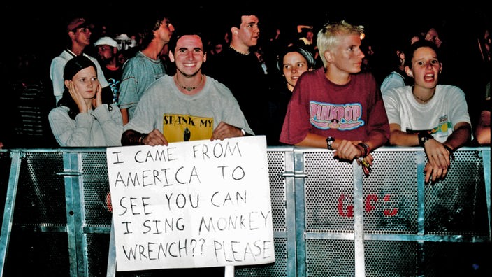 Fans an der Absperrung beim Konzert der Foo Fighters mit Transparent: "I came from America to see you. Can I sing Monkey Wrench? Please" - Ich bin aus Amerika gekommen, um euch zu sehen. Darf ich bitte Monkey Wrench singen?