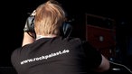 Mann mit Kopfhörern und Rockpalast-Shirt von hinten