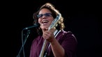 Sängerin der Alabama Shakes mit getönter Brille und Gitarre singt ins Mikrofon und lacht