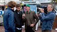 Der Moderator und der Kameramann des Rockpalastes interviewen zwei Mitglieder der "Shout Out Louds" auf der Straße vor einem Fotoautomaten.