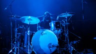 Schlagzeuger in blauem Bühnenlicht beim trommeln