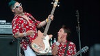 Der Bassist der Me First & The Gimme Gimmes posiert mit seinem Danelectro DC Bass, im Hintergrund sieht man den Gitarristen etwas über die Bühne rufen