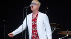 Sänger der Me First & The Gimme Gimmes singt ein lautes O ins Mikrofon, hat ein schönes weißes Jacket und ein Hawaii-Hemd an