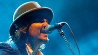 Der Sänger der Band Wilco im Profil am Mikrofon.