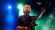 Der Sänger und Gitarrist der Band Nada Surf performt vor dem grünen Licht einer Lampe im Hintergrund.