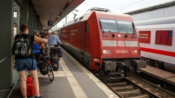 Das Bild zeigt einen Bahnhof. Ein Zug fährt vom Gleis ab. 