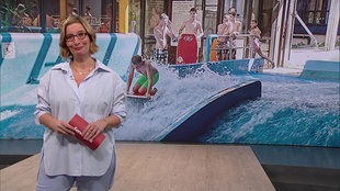 Die Moderatorin Yvonne Willicks steht im Servicezeit-Fernsehstudio. Im Hintergrund sind Kinder im Freibad zu sehen.