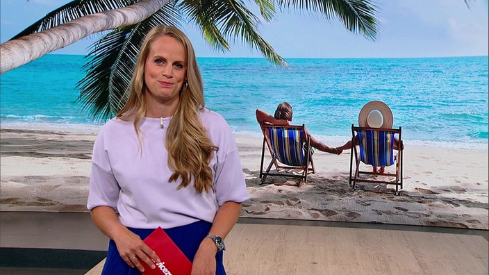 Svenja Kellershohn steht im Servicezeit-Studio. Im Hintergrund ist ein Päarchen am Strand abgebildet. 